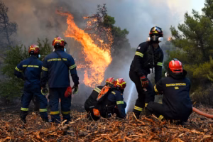 Greece wildfire helicopter drops water over a smoke-filled forest near Porto Germeno