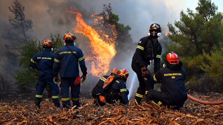 Greece wildfire helicopter drops water over a smoke-filled forest near Porto Germeno
