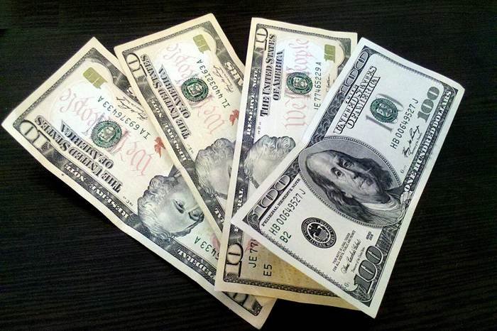 Moneymaxxing illustrated by US dollar banknotes representing budgeting and saving