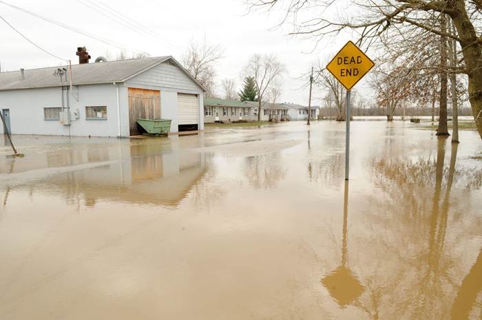 Indiana floods illustrated by a flooded street with submerged homes and a dead-end sign